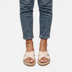 Women’s beige cross-strap espadrille slide sandals worn with rolled denim jeans