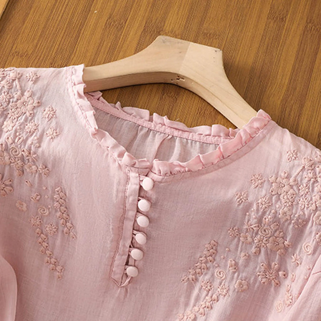 Pink embroidered blouse with ruffle neckline and button placket