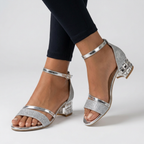 Open-toe sandals with silver metallic straps, silver glitter toe strap, and low block heels