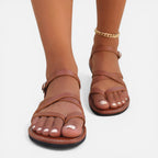Brown women’s toe-loop flat sandals with ankle strap and open toe