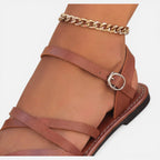 Brown toe-loop flat sandal with ankle strap, ring buckle, and chain detail