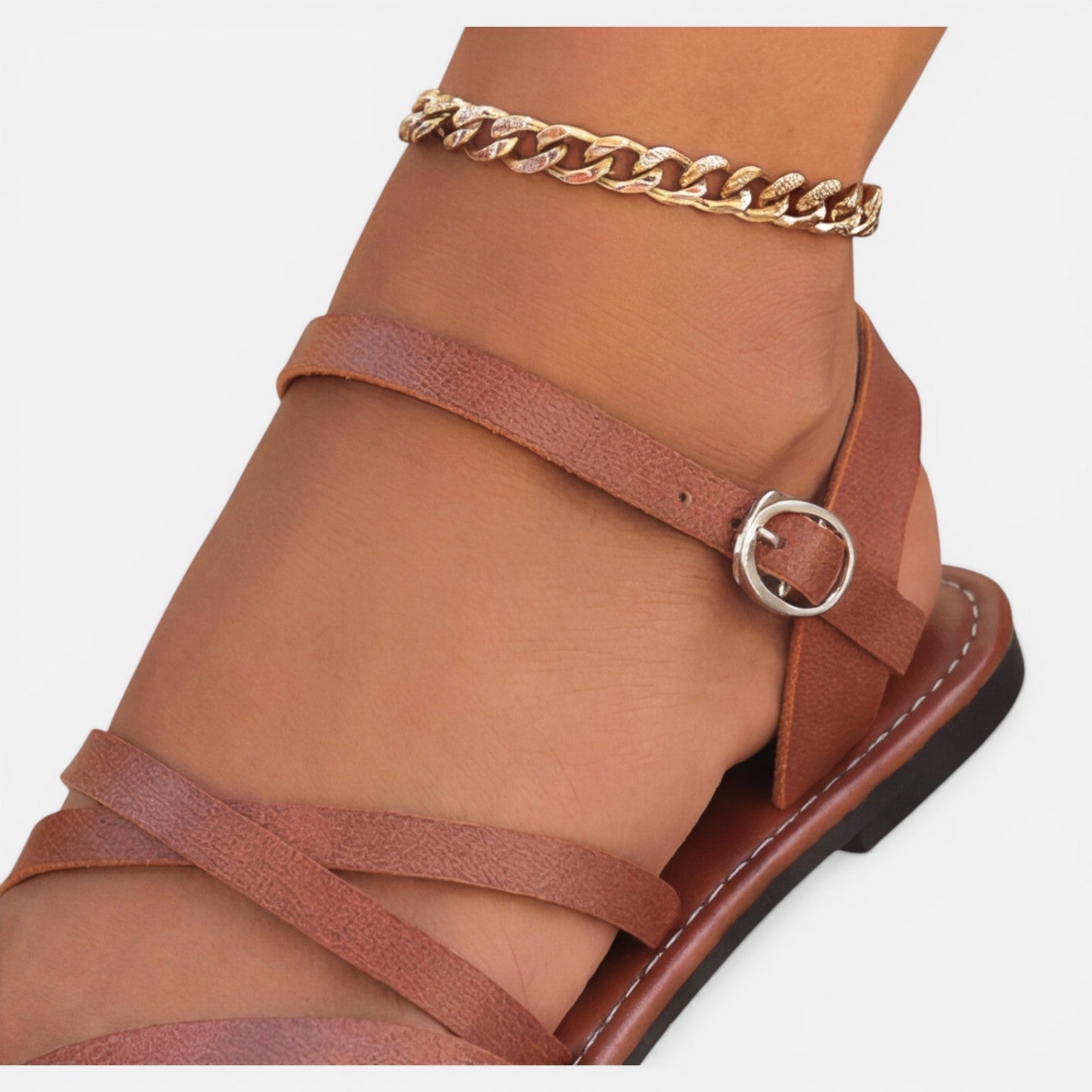 Brown toe-loop flat sandal with ankle strap, ring buckle, and chain detail
