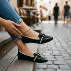 Women’s slip-on loafers in black with white trim, bow strap, and pointed toe