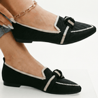 Black slip-on loafers with white trim and knotted bow