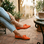 Women’s slip-on loafers in bright orange with bow strap detail and pointed toe