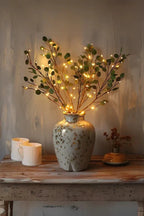 Olive LED branch centerpiece with warm white leaf lights in speckled ceramic vase