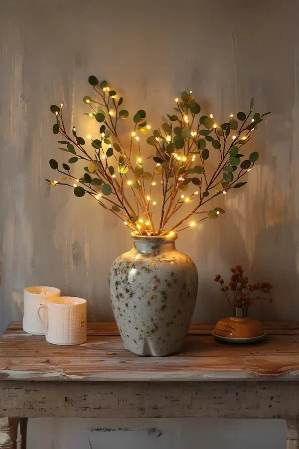 Olive LED branch centerpiece with warm white leaf lights in speckled ceramic vase