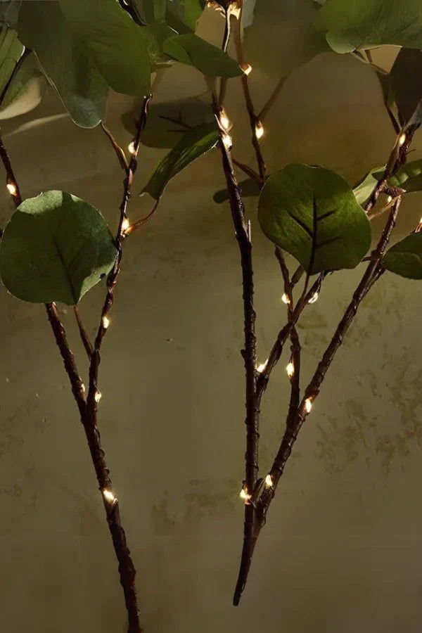 Olive LED branch centerpiece close-up: green leaves with warm lights on dark branches