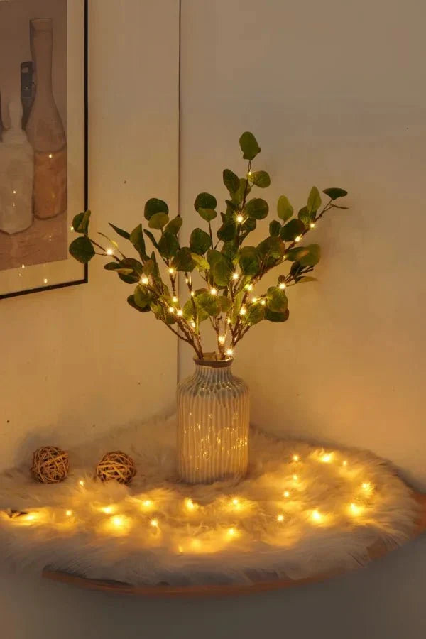 Olive LED branch centerpiece with warm white lights on branches in ribbed glass vase