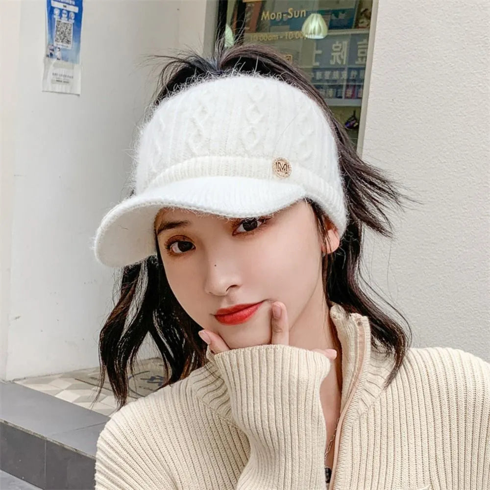 White cable-knit baseball cap with ribbed brim and small M logo badge