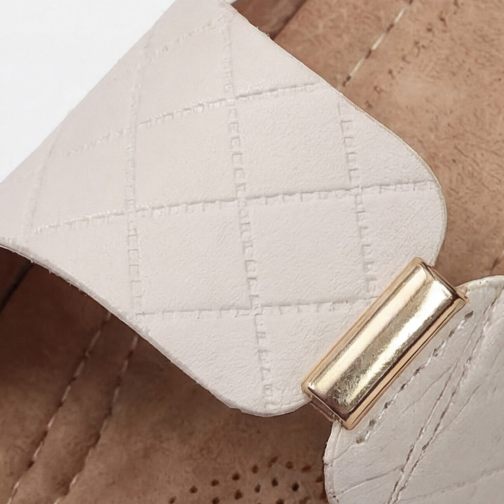 Beige leather sandal with quilted strap and gold buckle close-up