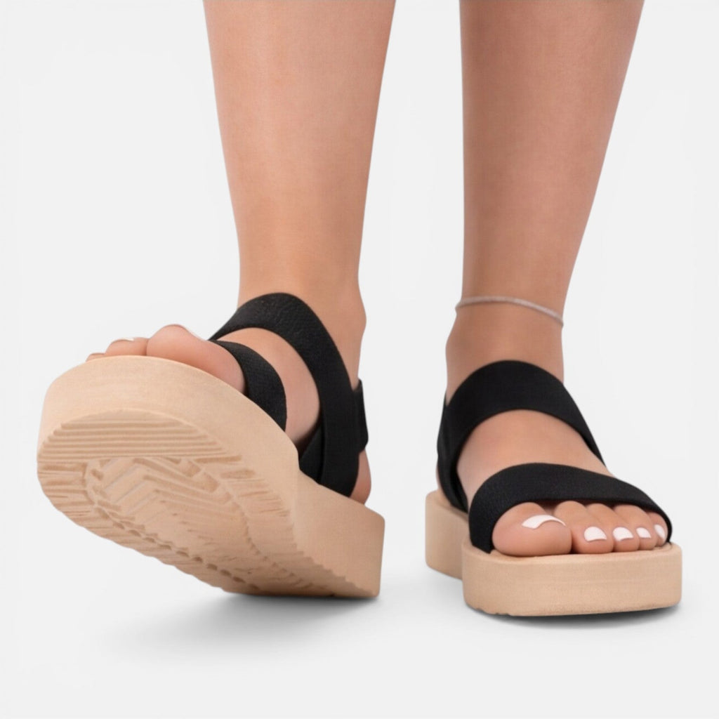 Women’s wedge sandals in black with two straps and visible textured tread sole