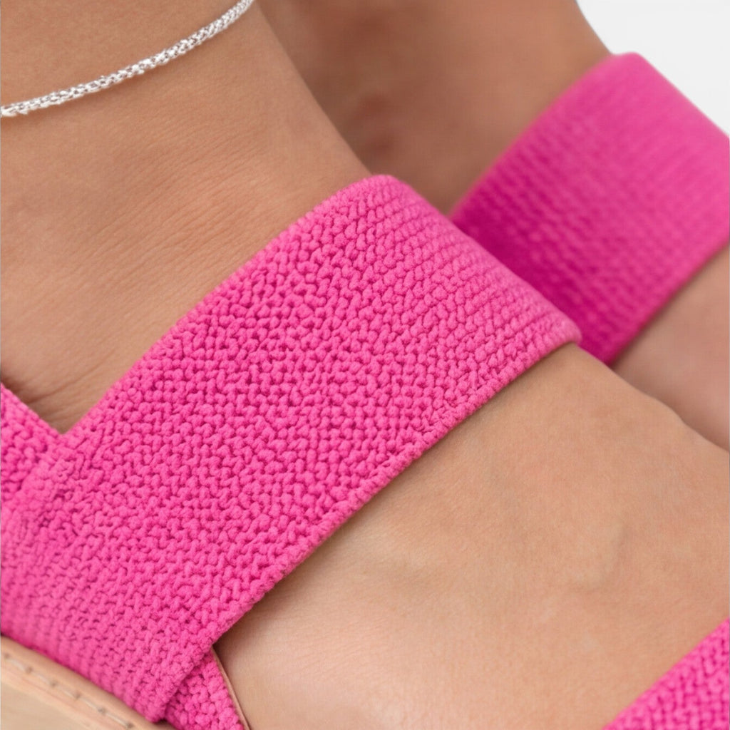 Women’s wedge sandals detail: bright pink textured strap and wide band across foot