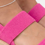 Women’s wedge sandals detail: bright pink textured strap and wide band across foot