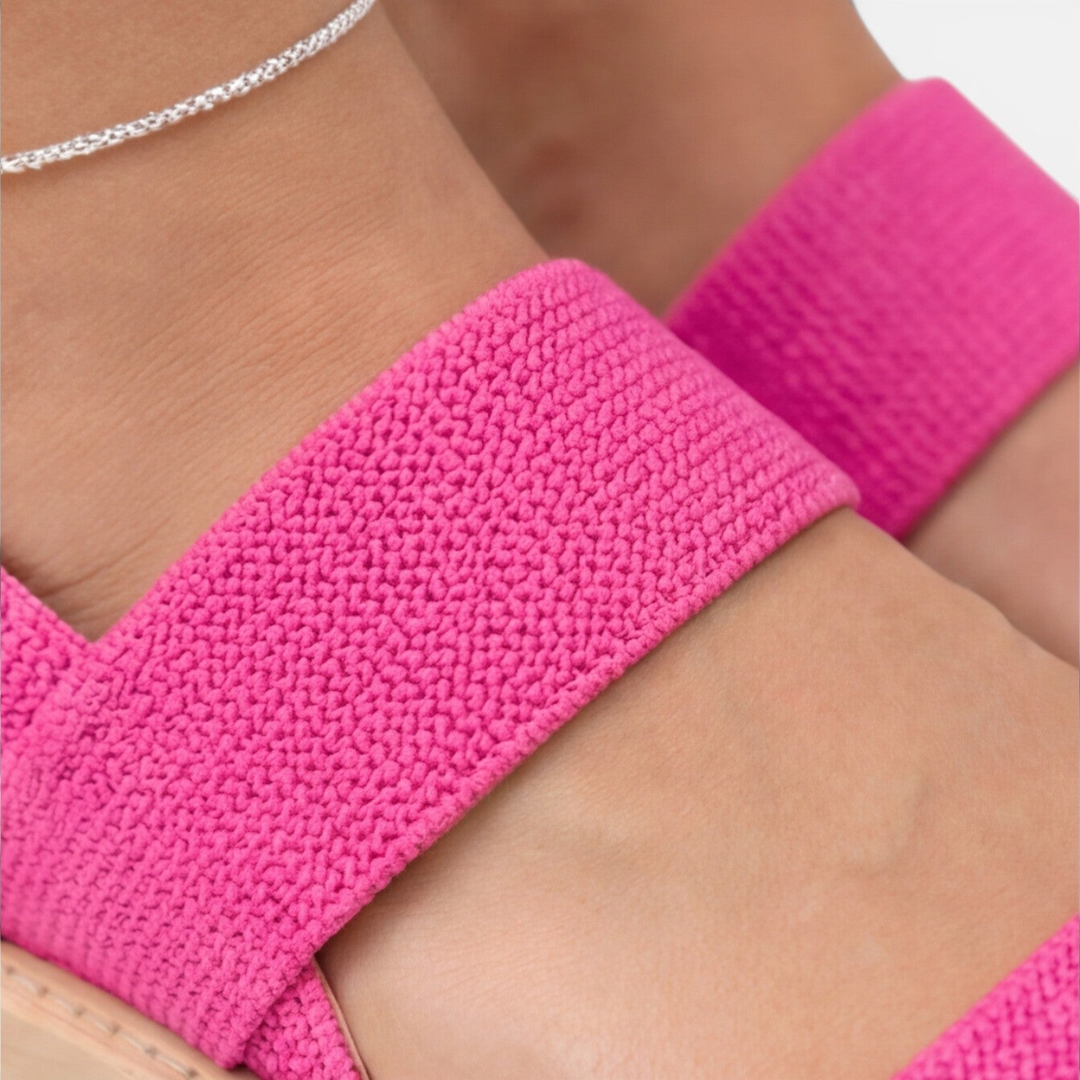 Women’s wedge sandals detail: bright pink textured strap and wide band across foot