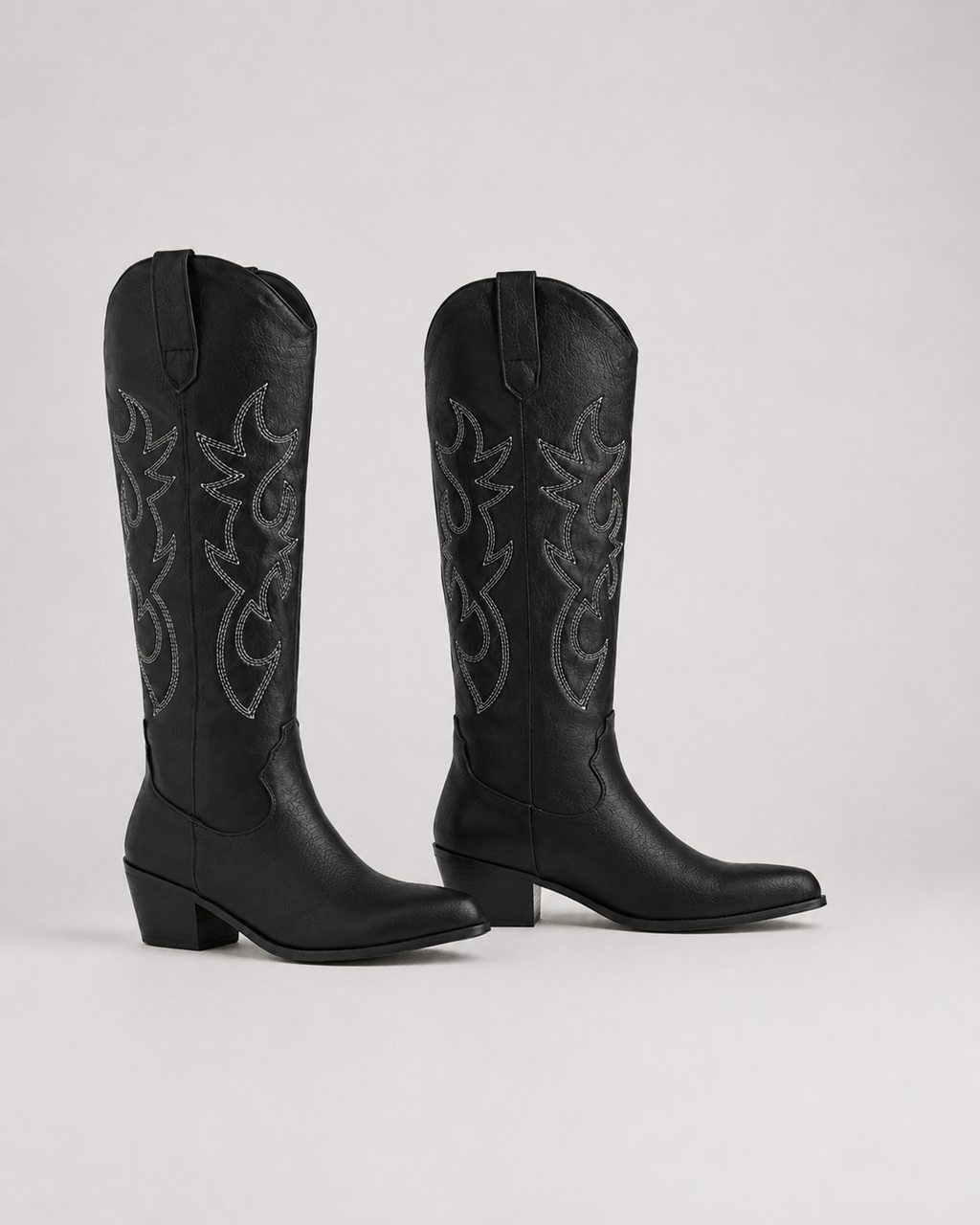 Black knee-high cowboy boots with stitched embroidered scroll pattern and low heel