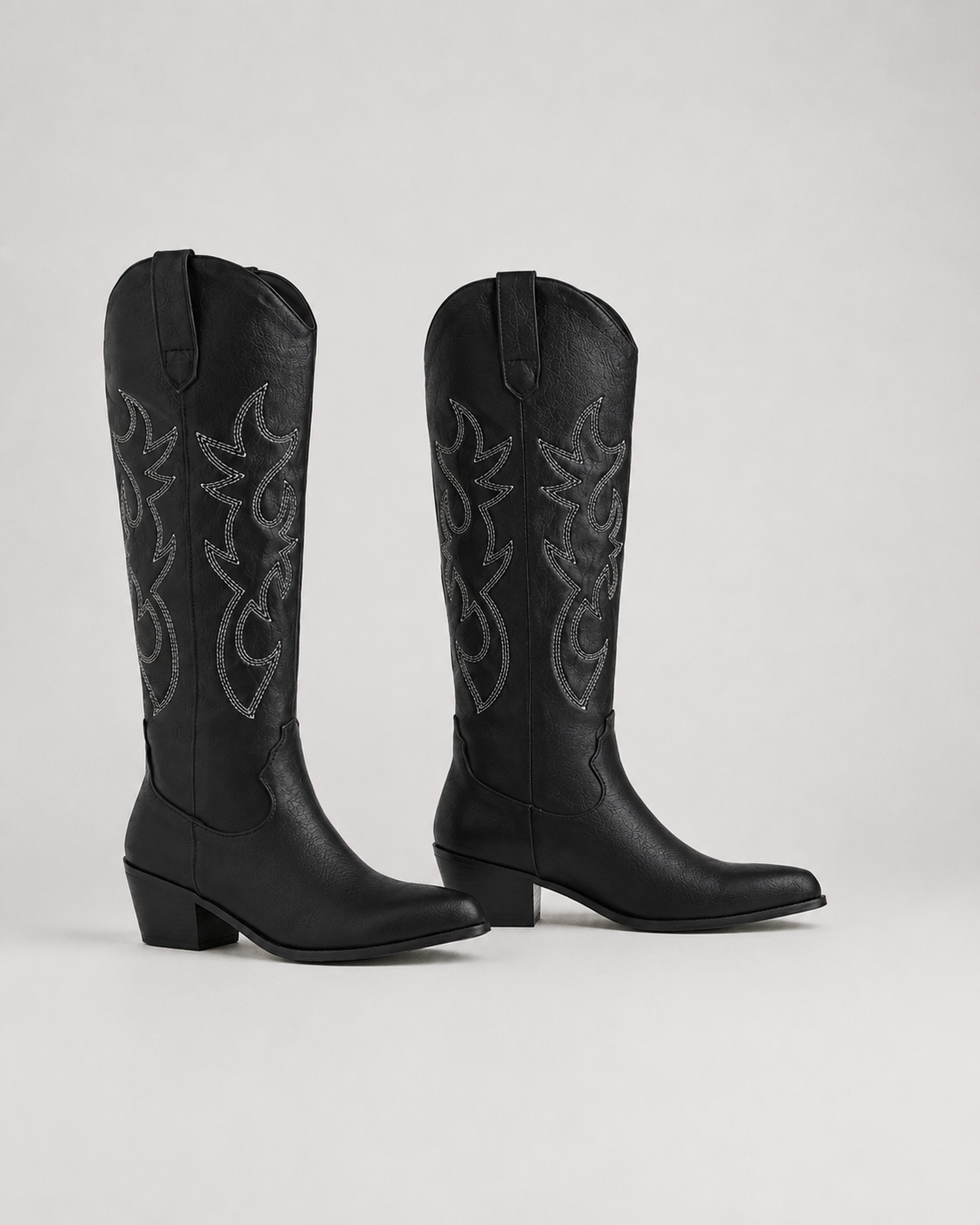 Black knee-high cowboy boots with stitched embroidered scroll pattern and low heel