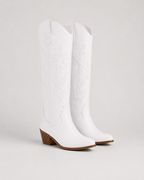 White knee-high cowboy boots with embroidered swirl pattern and low block heel