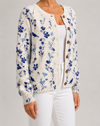 Beige floral knit cardigan with blue bird print, button-front, ribbed hem.