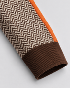 Ribbed knit cuff on herringbone sweater sleeve with dark brown and orange trim