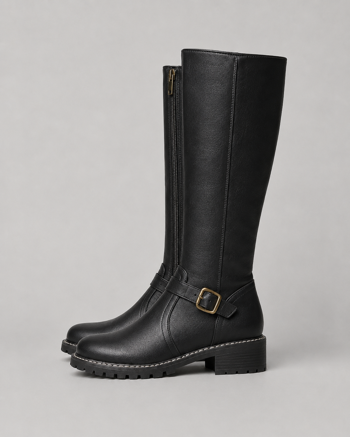 Black knee-high buckle boot with side zip, buckle strap and lug sole.