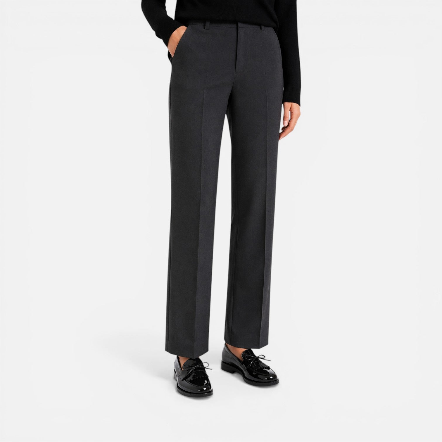 Black patent loafers on feet with straight-leg trousers, round toe slip-on