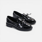 Black patent slip-on loafers with tassel fringe and round toe, low heel