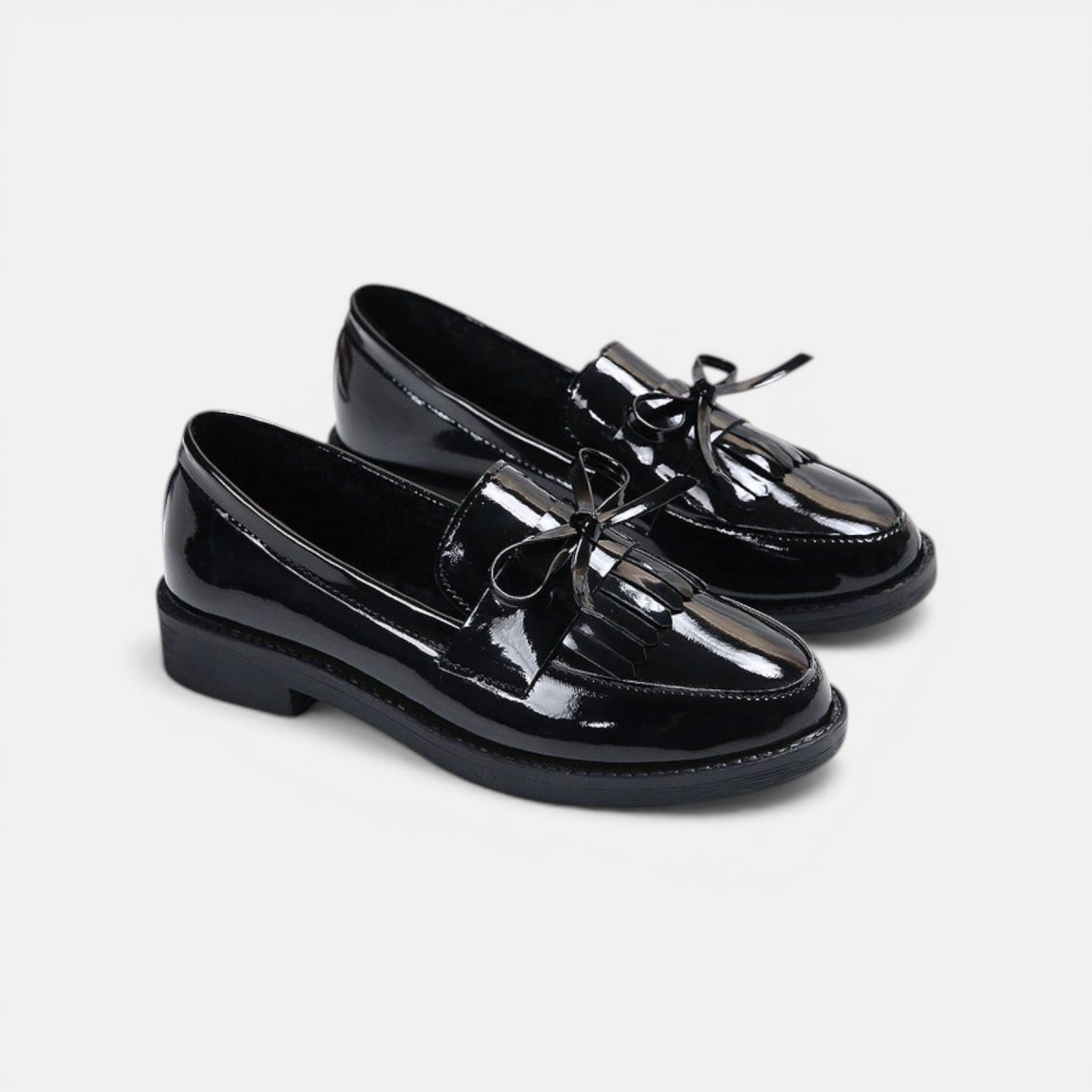 Black patent slip-on loafers with tassel fringe and round toe, low heel