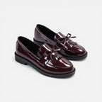 Burgundy patent slip-on loafers with tassel fringe and round toe, low heel