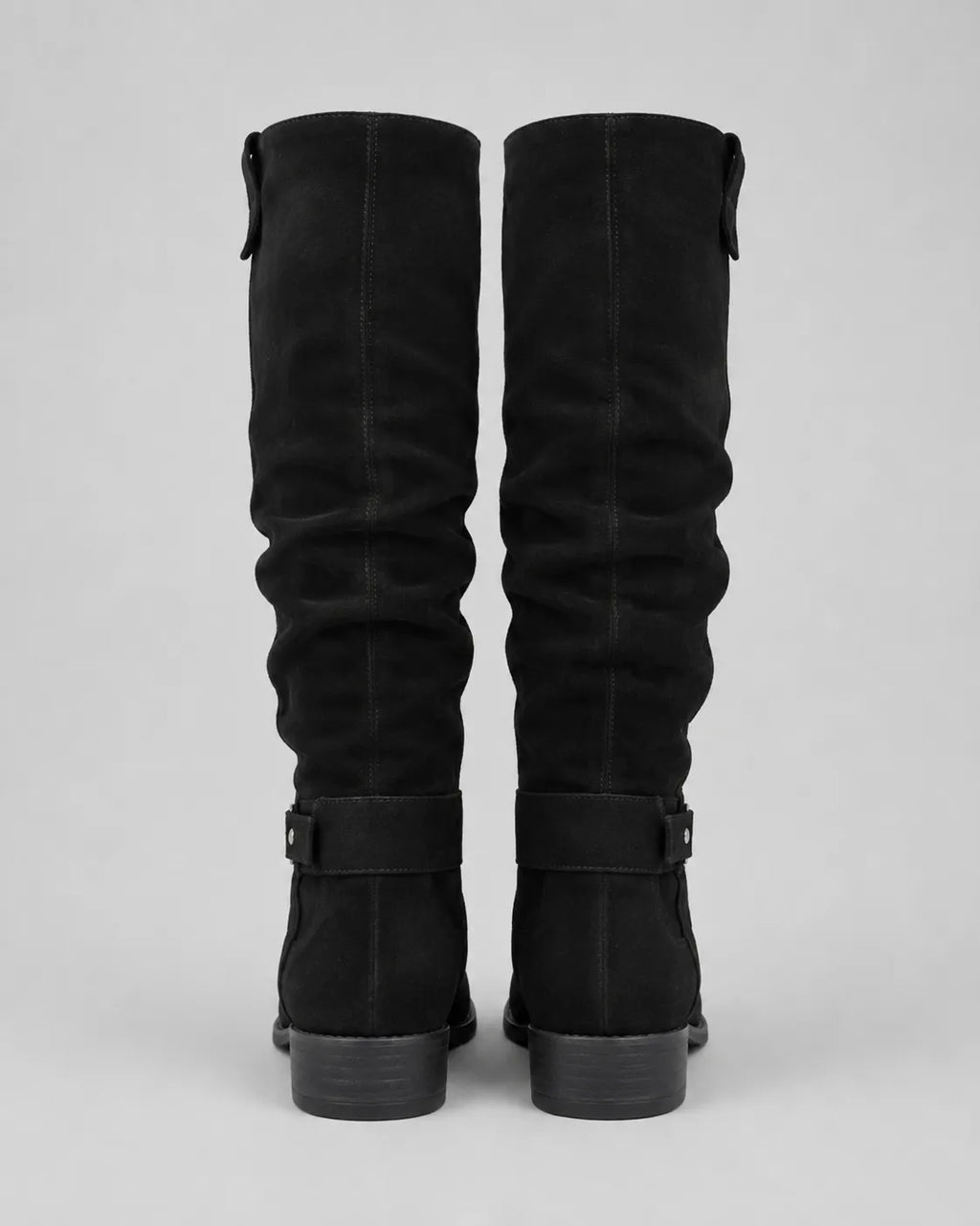 Pair of black suede knee-high boots with buckle strap at shaft