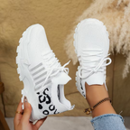 Women's sneakers in white with lace-up, black printed knit panel, chunky white sole.