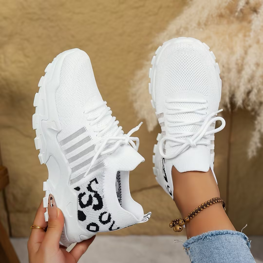 Women's sneakers in white with lace-up, black printed knit panel, chunky white sole.