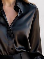 Black satin long-sleeve blouse close-up with pointed collar and button placket