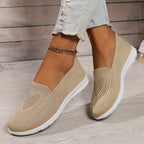 Beige low-top slip-on sneakers with textured knit upper and white rubber sole.