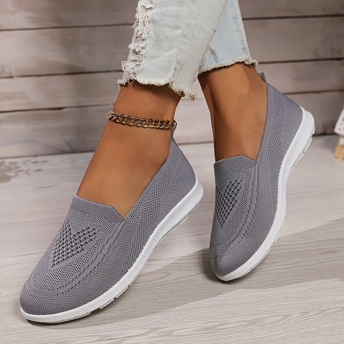 Grey low-top slip-on sneakers with textured knit upper and white rubber sole.