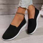 Black low-top slip-on sneakers with textured knit upper and white rubber sole.