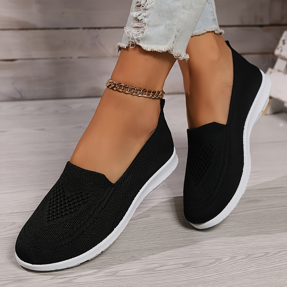 Black low-top slip-on sneakers with textured knit upper and white rubber sole.