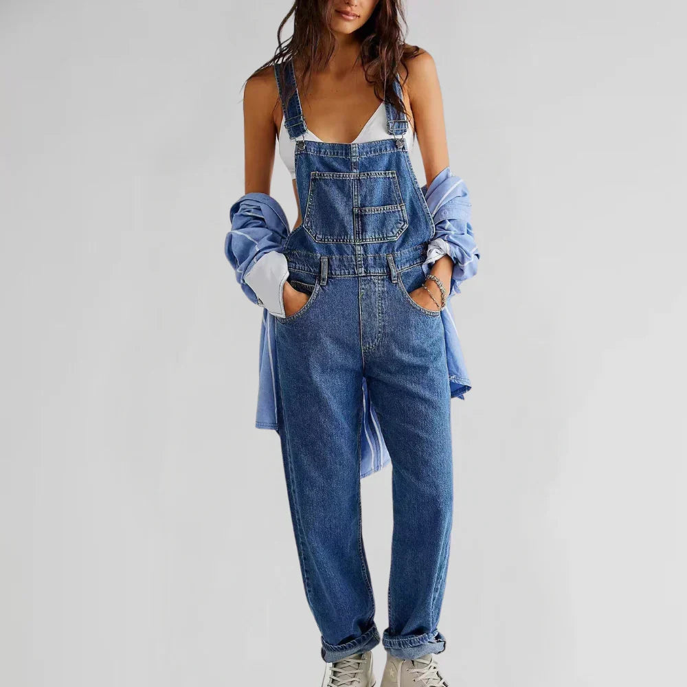 Blue denim strap jumpsuit with bib front, button placket, and relaxed wide-leg fit