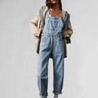 Light blue denim jumpsuit with square neck, bib front pockets, and wide-leg legs