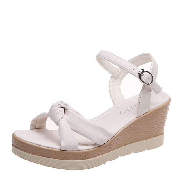 White platform wedge sandal with ankle strap and round buckle, open toe