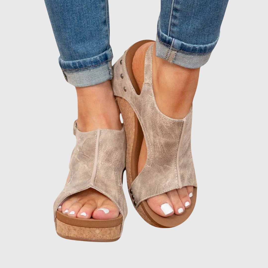Beige cushioned wedge sandals with open toe, perforated strap, and adjustable buckle.