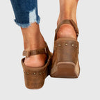 Brown wedge sandals from the back with ankle strap buckle and cushioned heel platform.