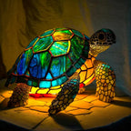 Turtle-shaped stained-glass table lamp with green, blue, and orange glowing shell