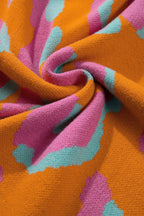 Close-up knit fabric in orange with pink and teal leopard-style colorblock pattern.