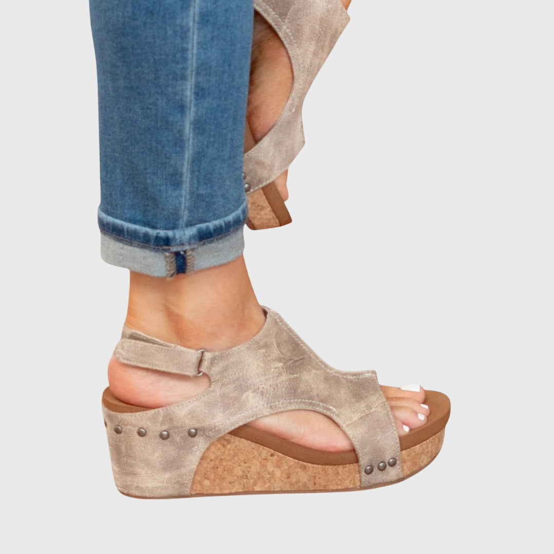 Beige open-toe wedge sandals with ankle strap and stud accents along the sides.