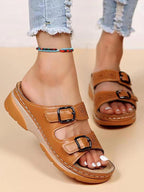 Tan double-buckle slip-on sandals with perforated straps and cushioned platform sole