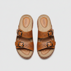 Tan double-buckle slide sandals with perforated leather straps and cushioned sole