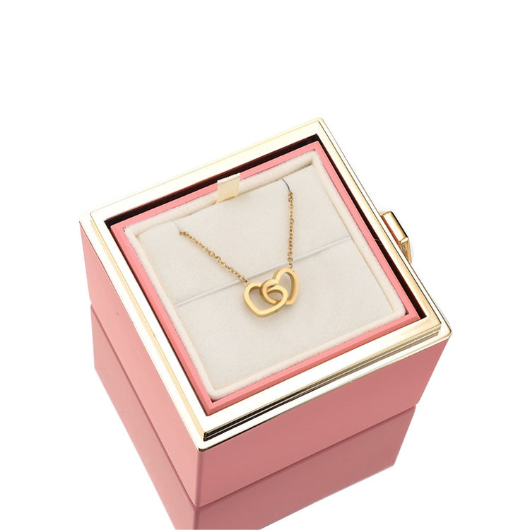 Pink jewelry gift box with gold heart pendant necklace on white display pillow