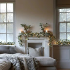 Eucalyptus garland with warm LED lights draped above sofa and fireplace opening