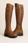 Knee-high brown boots with side buckle strap and chunky lug sole